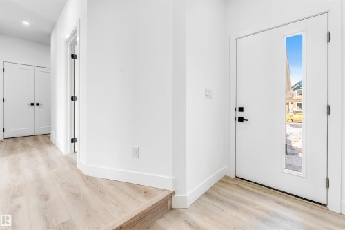 Welcoming entry with light-toned flooring, white walls, and a front door featuring a vertical window panel - 4102 67 Street, Beaumont, AB - Indoor Photo Showing Other Room
