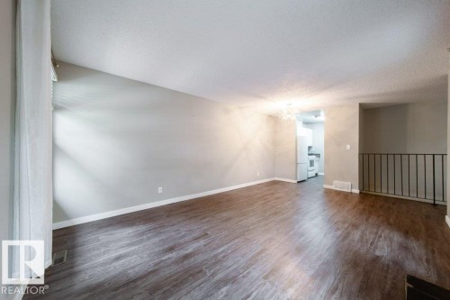 Spacious living area featuring wood-finish flooring, neutral wall tones, and white trim - 17106 108 St Nw, Edmonton, AB - Indoor Photo Showing Other Room