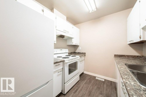 Kitchen featuring wood-finish flooring, white cabinetry, a double-basin stainless steel sink, and light-toned countertops - 17106 108 St Nw, Edmonton, AB - Indoor Photo Showing Kitchen With Double Sink