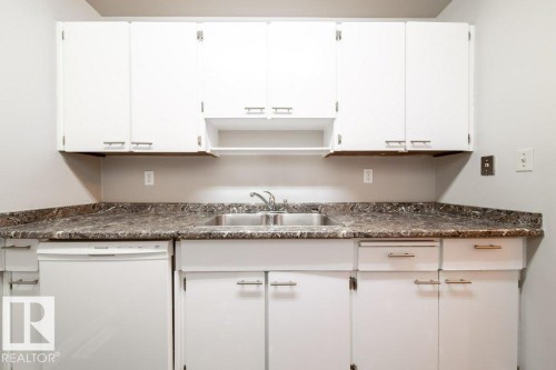 Kitchen area with white cabinetry, a double basin stainless steel sink, a stainless steel faucet, and a white dishwasher - 17106 108 St Nw, Edmonton, AB - Indoor Photo Showing Kitchen With Double Sink