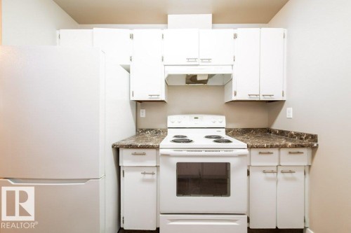 Kitchen featuring white cabinetry with brushed nickel hardware, white electric range with overhead exhaust, and a white refrigerator - 17106 108 St Nw, Edmonton, AB - Indoor Photo Showing Kitchen