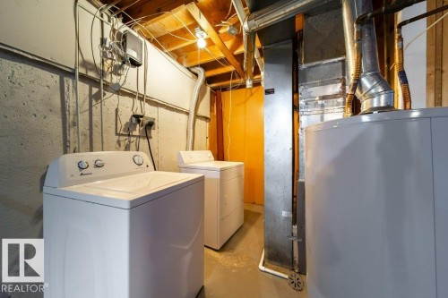 Dedicated laundry area featuring a top-load washing machine and dryer, alongside a water heater and exposed utility infrastructure - 17106 108 St Nw, Edmonton, AB - Indoor Photo Showing Laundry Room