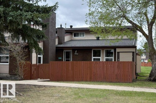 Two-story residence featuring a brown wood fence, tan siding, and a dark shingle roof - 17106 108 St Nw, Edmonton, AB - Outdoor