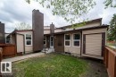 Rear exterior featuring light beige siding, exposed brick accents, and a prominent brown chimney structure - 17106 108 St Nw, Edmonton, AB  - Outdoor 