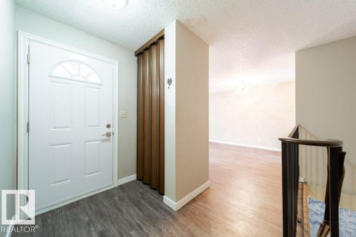 Entryway featuring a white paneled door with an arched transom window, wood-finish flooring, and a folding closet door - 17106 108 St Nw, Edmonton, AB - Indoor Photo Showing Other Room