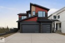 Modern multi-level exterior featuring a dark gray and red facade, stone accents, black-framed windows, and two dark gray garage doors with frosted glass inserts - 17108 2 Street, Edmonton, AB  - Outdoor 