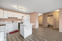 Open-concept living area featuring a kitchen with white cabinetry and a central island with countertop seating - 