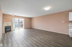 Spacious room featuring wood-finish flooring, a built-in electric fireplace with a white mantel, and a sliding glass door providing access to an outdoor area - 
