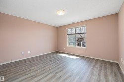 Spacious room featuring wood-finish flooring, a large window with blinds, and a flush-mount ceiling light fixture - 