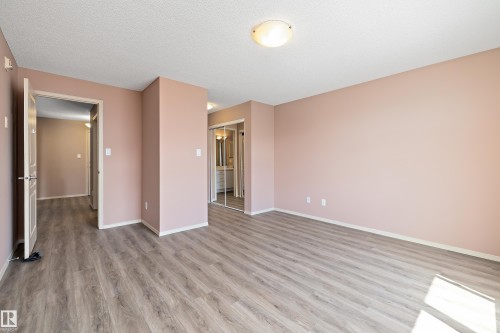 Spacious room with wood-finish flooring, a contemporary ceiling light fixture, and light-toned wall paint - 406 16035 132 Street, Edmonton, AB - Indoor Photo Showing Other Room