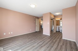 Expansive room featuring wood-finish flooring, a neutral wall color, and a full bathroom with a vanity and mirror - 