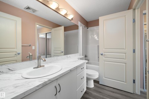 Bathroom featuring a white vanity with a patterned countertop, undermount sink, and brushed nickel faucet - 406 16035 132 Street, Edmonton, AB - Indoor Photo Showing Bathroom
