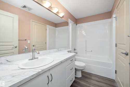 Bathroom vanity with a white countertop and integrated sink, complete with a chrome faucet - 406 16035 132 Street, Edmonton, AB - Indoor Photo Showing Bathroom