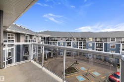 Private balcony with glass panel railing and concrete flooring overlooking a multi-story residential building with a central courtyard - 