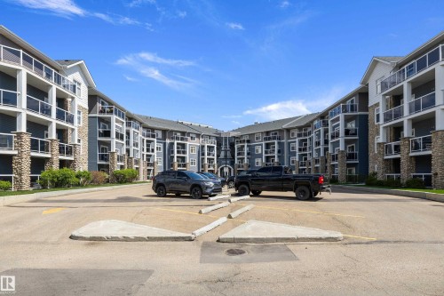 Multi-story residential building featuring dark blue siding, white trim, and stone accents - 406 16035 132 Street, Edmonton, AB - Outdoor With Balcony With Facade