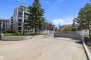 Multi-story building featuring stacked balconies with glass railings, stone veneer accents, and a sloped concrete entrance to subterranean parking - 406 16035 132 Street, Edmonton, AB  - Outdoor With Balcony 