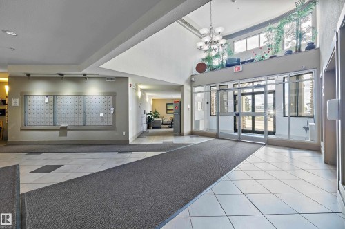 Spacious lobby entrance featuring a vaulted ceiling and a modern chandelier - 406 16035 132 Street, Edmonton, AB - Indoor Photo Showing Other Room