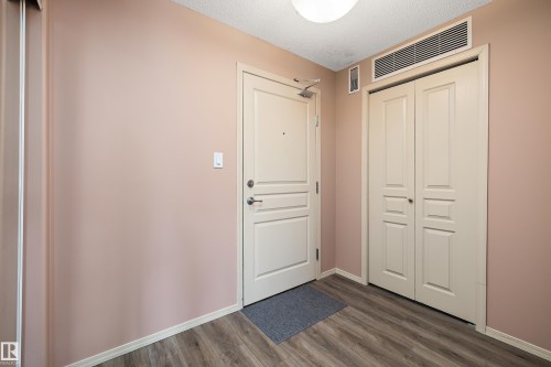Entryway featuring wood-finish flooring, a flush-mount ceiling light, and a built-in closet with bi-fold doors - 406 16035 132 Street, Edmonton, AB - Indoor Photo Showing Other Room