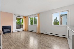 Living area featuring wood-finish flooring, a built-in fireplace, and abundant natural light from multiple windows and a sliding glass door - 