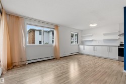 Open-concept living area with wood-finish flooring, large windows, and contemporary overhead lighting - 
