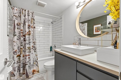 Bathroom featuring a white subway tile shower surround, a white bathtub, and hexagonal floor tiling - 217 14819 51 Avenue, Edmonton, AB - Indoor Photo Showing Bathroom