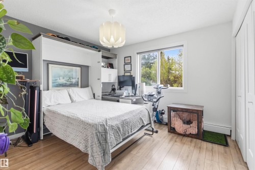 Bedroom featuring wood-finish flooring and a built-in wall unit - 217 14819 51 Avenue, Edmonton, AB - Indoor Photo Showing Bedroom
