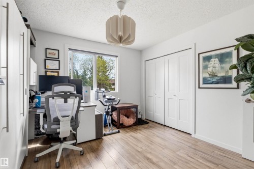 Spacious room featuring wood-finish flooring, a large window, a ceiling light fixture, and bifold closet doors - 217 14819 51 Avenue, Edmonton, AB - Indoor Photo Showing Office