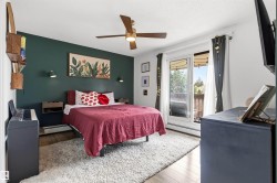 Room featuring wood-finish flooring, a full-light sliding door with access to an outdoor space, a ceiling fan with integrated lighting, and a painted accent wall - 