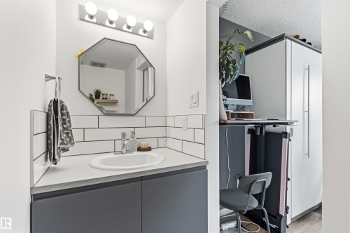 Modern vanity featuring a built-in sink, dark cabinetry, and white countertop - 217 14819 51 Avenue, Edmonton, AB - Indoor Photo Showing Bathroom