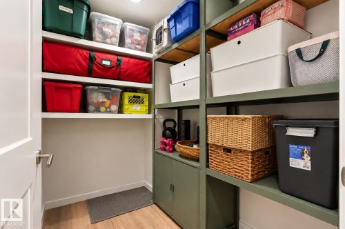 Dedicated storage area featuring built-in shelving, wood-finish flooring, recessed lighting, and a white interior door with brushed nickel hardware - 217 14819 51 Avenue, Edmonton, AB - Indoor