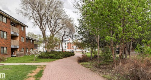 Brick exterior building with multiple balconies, a paver walkway, mature trees, and landscaping - 217 14819 51 Avenue, Edmonton, AB - Outdoor