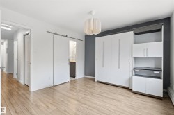 Wood-finish flooring throughout, complemented by a white ceiling and a contemporary pendant light fixture - 