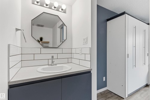 Bathroom vanity featuring a vessel sink, subway tile backsplash, and dark blue cabinetry - 217 14819 51 Avenue, Edmonton, AB 