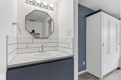Bathroom vanity featuring a vessel sink, subway tile backsplash, and dark blue cabinetry - 