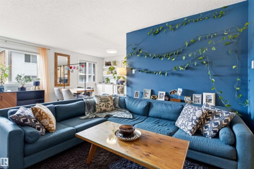 Spacious living area featuring a prominent accent wall, recessed lighting, and large windows - 217 14819 51 Avenue, Edmonton, AB - Indoor Photo Showing Living Room