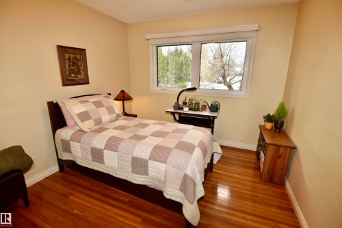 Bedroom featuring wood-finish flooring, a double-pane window, and light-toned wall paint - 13910 101A Avenue, Edmonton, AB - Indoor Photo Showing Bedroom