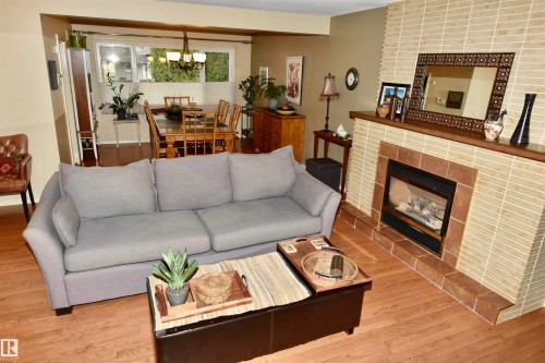 Living area featuring wood-finish flooring and a tiled fireplace surround with a hearth - 13910 101A Avenue, Edmonton, AB - Indoor Photo Showing Living Room With Fireplace