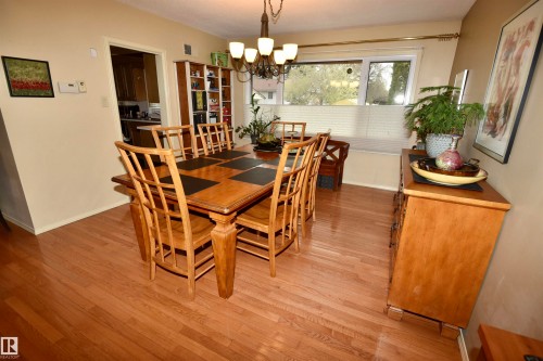 Spacious dining area featuring wood-finish flooring, a multi-light chandelier, and a wide window with a built-in window seat - 13910 101A Avenue, Edmonton, AB - Indoor Photo Showing Dining Room