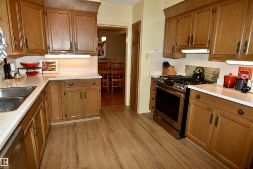 Kitchen featuring wood-finish cabinetry, white countertops, stainless steel range, and wood-finish flooring - 13910 101A Avenue, Edmonton, AB - Indoor Photo Showing Kitchen With Double Sink