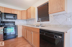 Kitchen featuring wood-finish cabinetry, black appliances, laminate countertops, and a diagonal tile backsplash - 