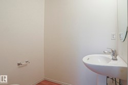 White wall finishes complement the wood-finish flooring in this space featuring a modern pedestal sink with a chrome faucet - 