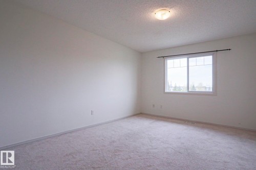Carpeted room with a double window featuring white trim and a dark-toned curtain rod - 1627 Melrose Place Sw, Edmonton, AB - Indoor Photo Showing Other Room