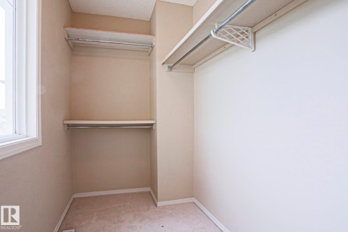 Walk-in closet featuring carpet flooring and a window with white trim - 1627 Melrose Place Sw, Edmonton, AB - Indoor With Storage