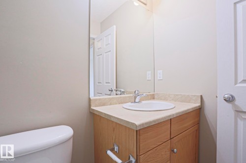 Bathroom vanity featuring an integrated sink, laminate countertop, and wood-finish cabinetry - 1627 Melrose Place Sw, Edmonton, AB - Indoor Photo Showing Bathroom