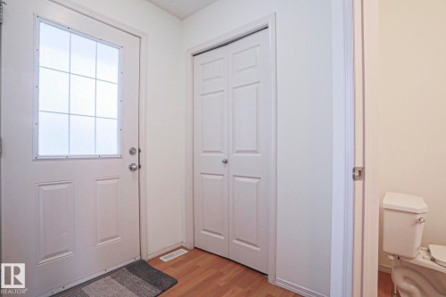 Entryway featuring wood-finish flooring, white paneled doors, and a front door with a decorative glass insert - 1627 Melrose Place Sw, Edmonton, AB - Indoor Photo Showing Other Room