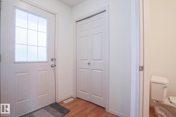 Entryway featuring wood-finish flooring, white paneled doors, and a front door with a decorative glass insert - 