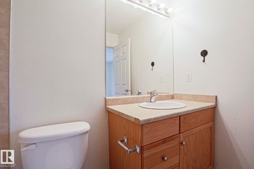 Bathroom vanity featuring a light wood-finish cabinet with storage, a surface-mounted sink, and a laminate countertop - 1627 Melrose Place Sw, Edmonton, AB - Indoor Photo Showing Bathroom