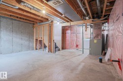 Unfinished basement presenting concrete flooring, exposed ceiling joists, and structural framing - 