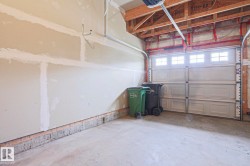 Attached garage featuring a concrete floor, light-colored walls, and an overhead garage door with upper window inserts - 