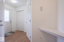 Entryway featuring wood-finish flooring, a contemporary ceiling light fixture, a built-in wall shelf, a modern thermostat, and multiple interior doors - 1627 Melrose Place Sw, Edmonton, AB  - Indoor Photo Showing Other Room 